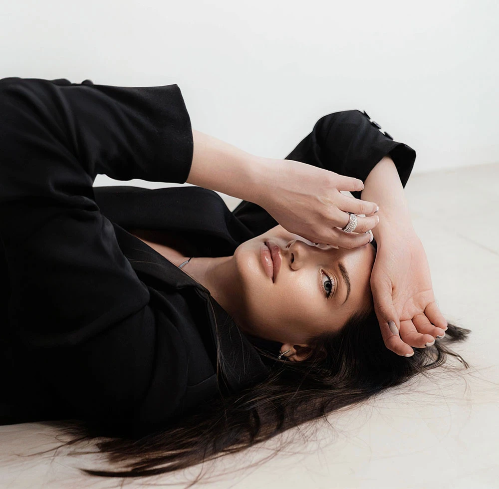 woman in all black laying on white floor | CA Aesthetics by Dr. Li