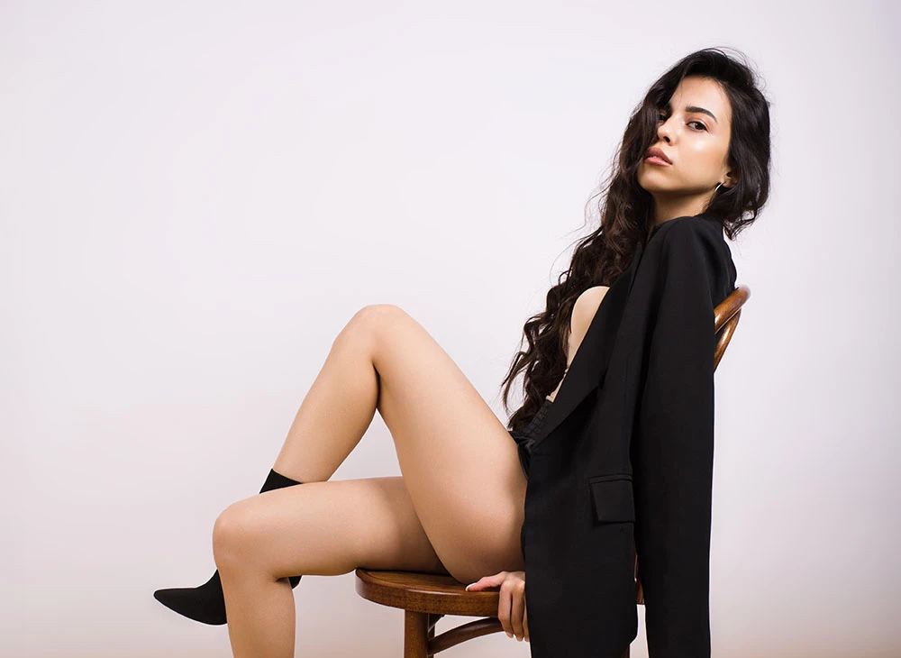 woman in all black leaning back in wooden chair | CA Aesthetics by Dr. Li